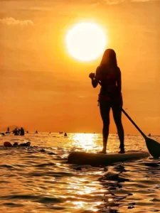 pessoa-praticando-stand-up-paddle-ao-pordo-sol-na-praia.webp